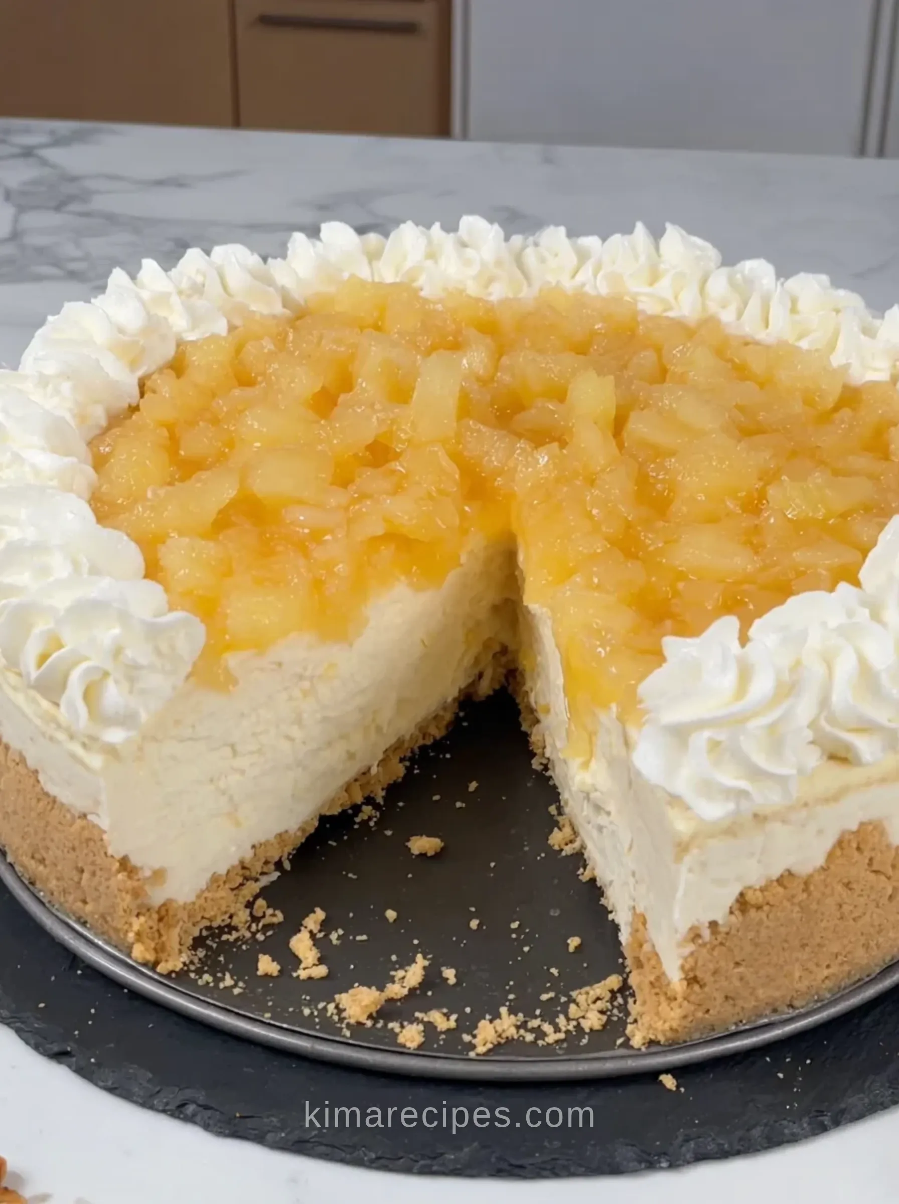 No oven pineapple cheesecake with a slice cut out, showing a creamy filling, Nilla wafer crust, piped whipped cream and a crushed pineapple topping