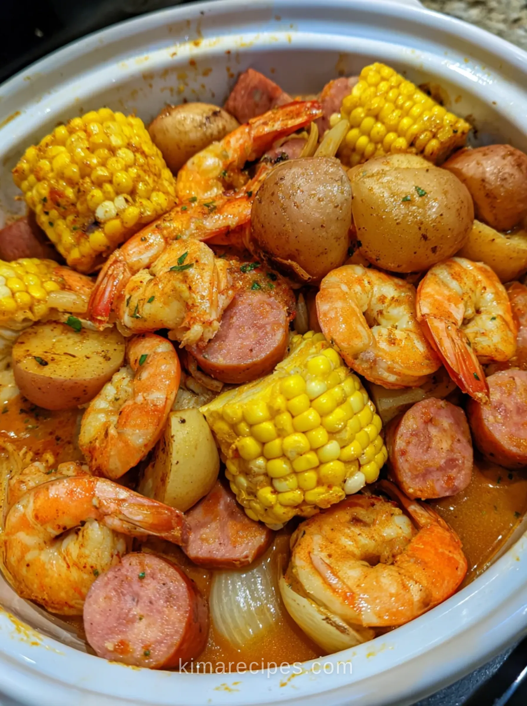 Crock-Pot shrimp boil with corn, potatoes and sausage in a white slow cooker with Old Bay broth