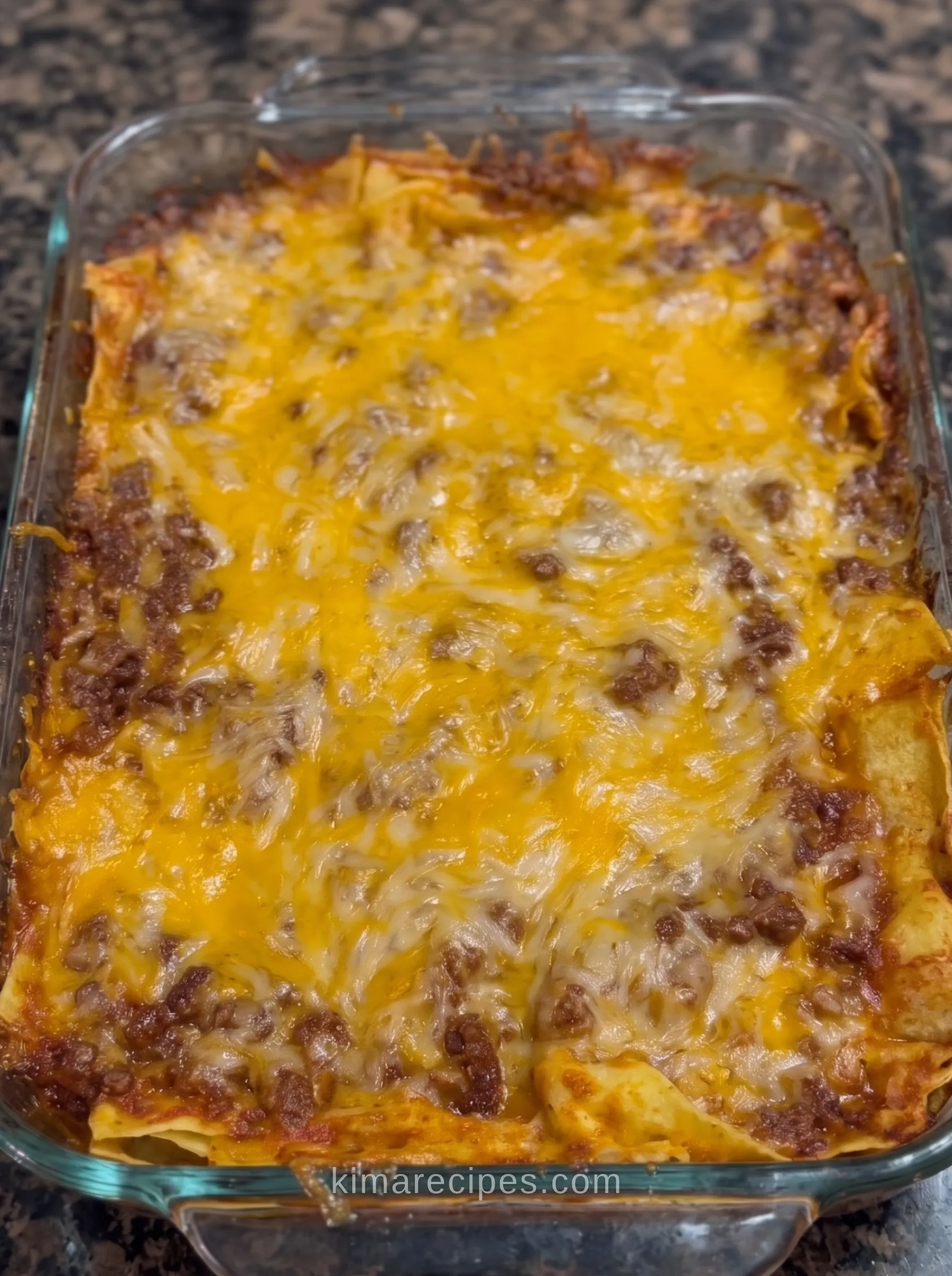 Easy Mexican lasagna fresh from the oven in a glass baking dish, with melted cheddar and Monterey Jack over ground beef and tortilla layers