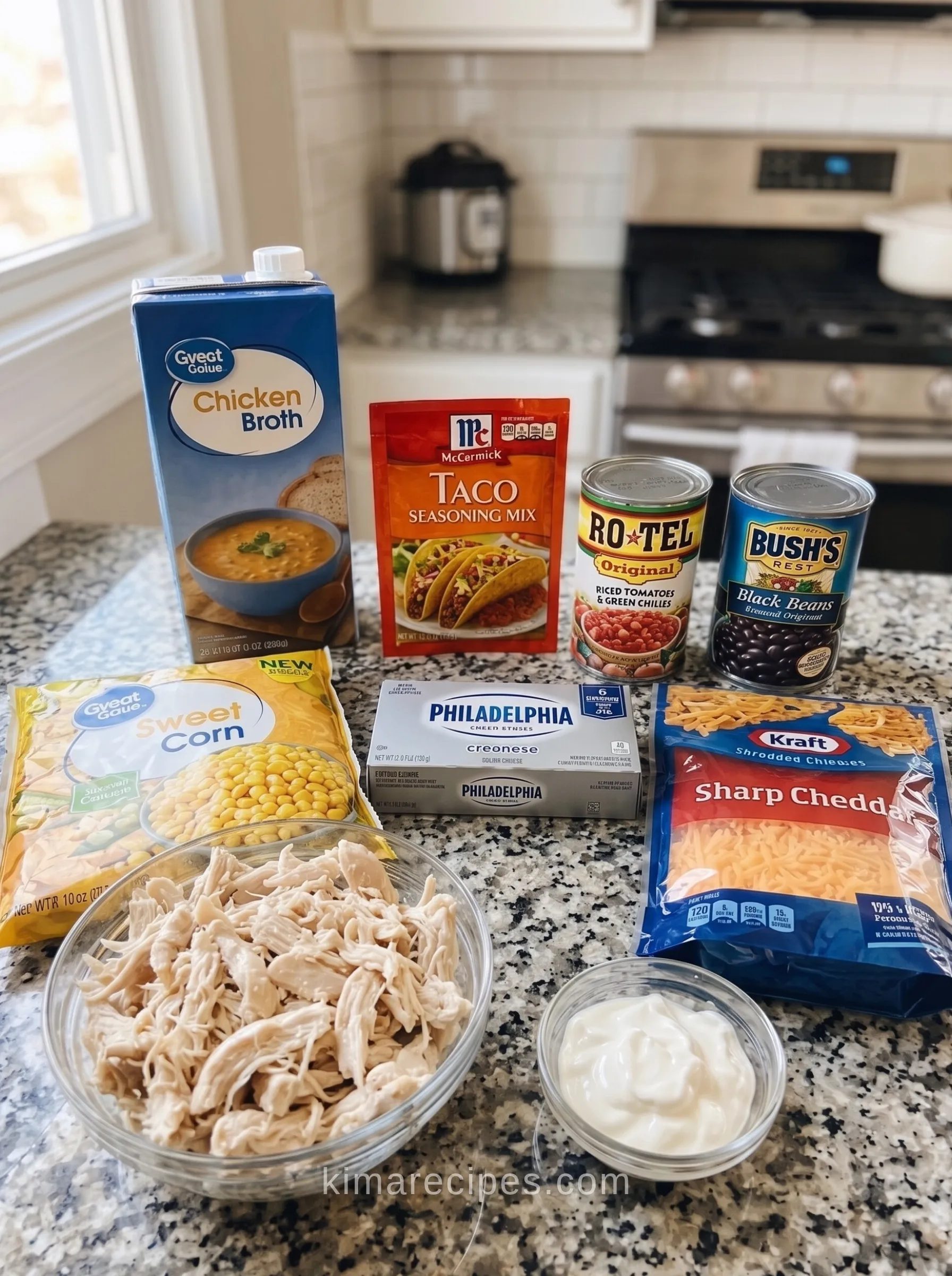 Ingredients for cheesy chicken enchilada soup laid out on a counter, including shredded chicken, broth, corn, beans, and cheese