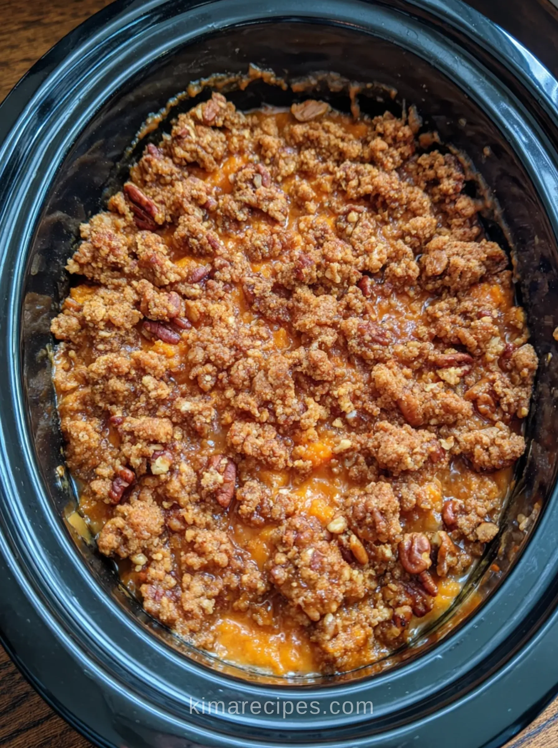 Slow cooker sweet potato casserole with a crumbly brown sugar pecan streusel topping in an oval Crock-Pot